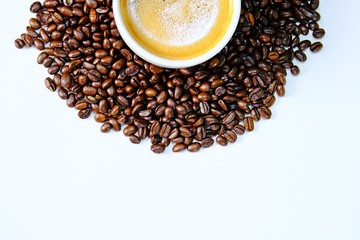 Top view cropped coffee cup filled with hot coffee surrounded by roasted coffee beans isolate on white background.