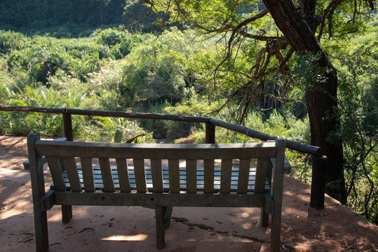 A bench overlooking the cliffs and dense vegetation along an African river. © Jason