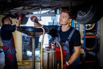 Car mechanic changes oil in a workshop