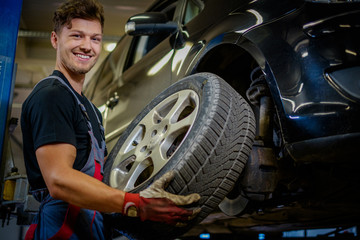 Car mechanic replacing wheel in a workshop