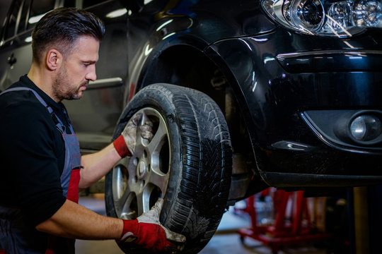 Car mechanic replacing wheel in a workshop