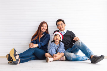 Merry Christmas and Happy Holidays! Cheerful parent and her cute daughter smiling and sitting on floor.