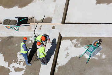 Uniformed workers clean sand on a construction site, top view.
