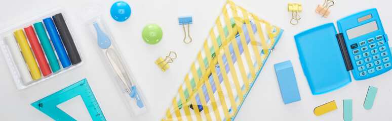 Panoramic shot of blue and yellow scattered school supplies with pencil case and calculator...