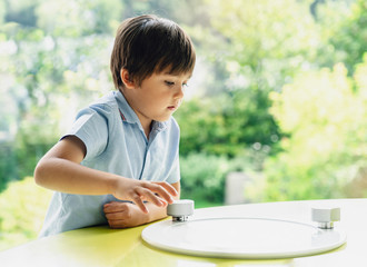 High key portrait of school kid playing game in playroomwith blurry natural background, Child holding bottom game with wondering face in a sunny room next to window, Learn and play, Education concept