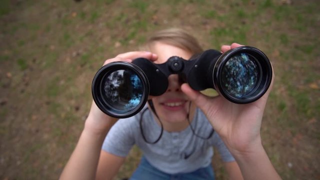 White handsome kid exploring nature outdoor using old black binocular. Slow motion full hd video footage.