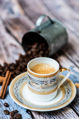 Tasse de café en porcelaine ancienne pot en métal cannelle et grains de café sur une table en bois vintage