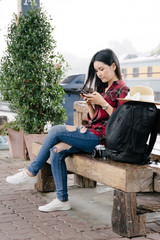 Young beautiful female travel photographer enjoys taking photo during her trip at railway station. Asian woman travel with camera having fun making pictures while waiting for train.