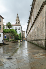 Fototapeta na wymiar Santiago de Compostela, Spain; August 9, 2019: Pilgrims and tourists walking on a rainy day street of old town of Santiago de Compostela