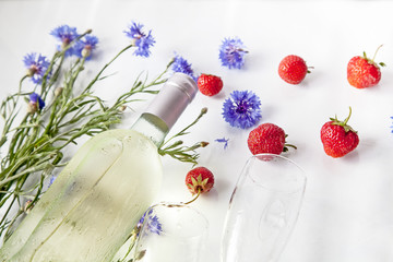 Obraz na płótnie Canvas white wine bottle strawberry flowers and glasses