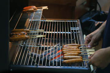 Grilling sausages on barbecue grill. BBQ in the garden. Bavarian sausages.