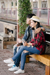 Couple of travel photographer enjoys taking photo during their trip at railway station. Asian  travelers with camera having fun making pictures while waiting for train.