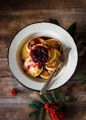 syrniki with jam in a plate on a wooden background