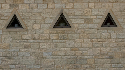 Triangular window in sand stone wall 