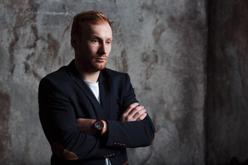 Portrait of a modern blonde young man in a classic suit. He is a little sad.