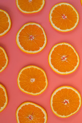 Background of sliced ripe oranges on a pink background vertical.
