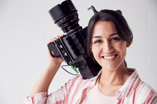 Portrait Of Female Videographer With Video Camera Filming Movie In White Studio