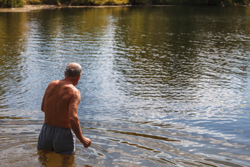 Healthy senior man swims in the lake