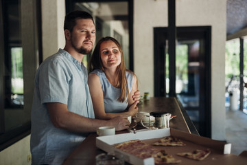 Couple standing near table with food leftovers