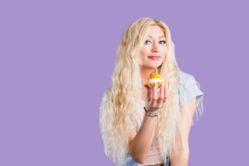 Happy lovely curly young woman holding birthday cupcake with candle