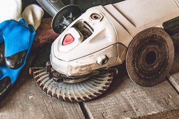 Electric cutting and grinding machine. Angle grinder with abrasive disc on wooden boards.