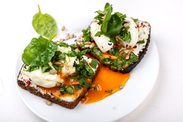 Sandwiches with poached eggs, cheese, spinach leaves, sesame seeds and seeds. Healthy breakfast or snack on the white background.