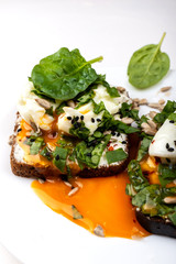 Sandwiches with poached eggs, cheese, spinach leaves, sesame seeds and seeds. Healthy breakfast or snack on the white background. Close-up.