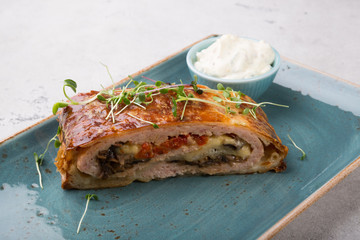 Slice of meat roll cake with sour cream