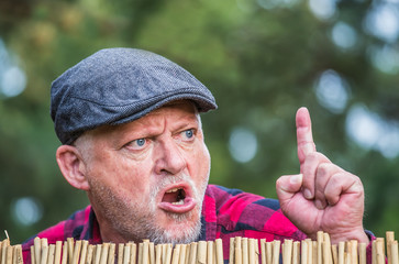 An evil, aggressive man watches his neighborhood over the garden fence. Concept dispute and...