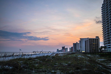 Fototapeta na wymiar pink purple and orange beach sunset in Orange Beach Alabama in the summer with beach condominiums and hotels and buildings on the strip