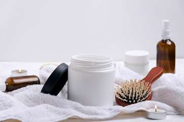 Fototapeta na wymiar Concept of hair care, products and tools.Cosmetics for hair on the white towel against white wall
