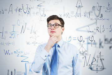 Thoughtful young man in glasses, formulas
