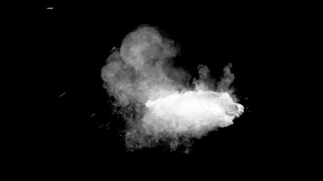 Bullet hits yellow powder causing dusty burst and scattering of pieces. The dust settles on the ground. Separated on pure black background, contains alpha channel.
