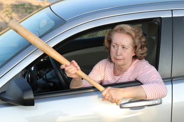 Angry mature female driver holding baseball bat