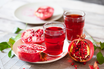 Pomegranate juice with fresh pomegranate fruits on wooden table