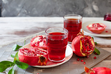Pomegranate juice with fresh pomegranate fruits on wooden table