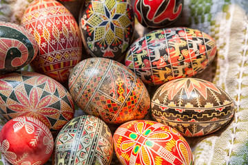 Fototapeta na wymiar Easter wooden eggs into national old Russian patterns on a plate with a kitchen towel. Flat lay composition of painted Easter eggs