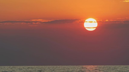 Sea sunset. Time lapse of the large sunset as the sun sets into the horizon above the sea.
