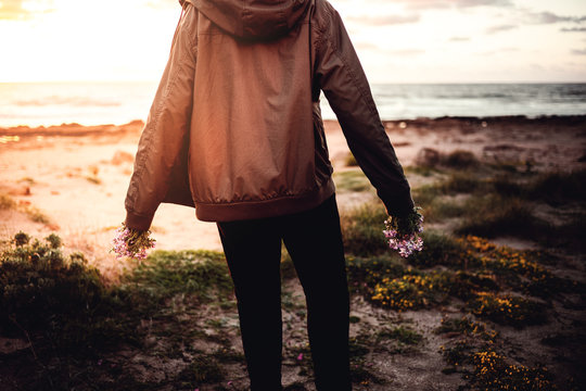 Mann mit Blumen in beiden h&auml;nden, am Meer beim sonnenuntergang
