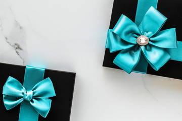 Luxury holiday gifts with emerald silk ribbon and bow on marble background
