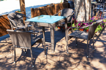 Beautiful wicker tables and chairs made of artificial rattan are in the street cafe.