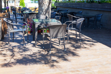 Beautiful wicker tables and chairs made of artificial rattan are in the street cafe.