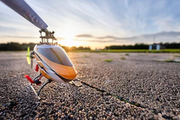 Fototapeten Ein RC-Helikopter, der während des Sonnenuntergangs an einem schönen Sommertag auf dem Boden steht © franconiaphoto