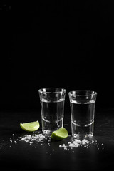 Vodka in shot glass on black background with a blank space for a text, Russian vodka with salt and lemon