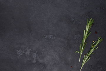 Fototapeta na wymiar Rosemary, pepper spices on dark concrete background. Cooking, menu, recipe concept. Top view, flat lay, mock up, copy space