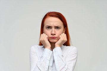 Close-up Portrait of a pretty red-haired girl, a happy young woman manager in a white shirt on a white background in studio. Smiling, showing different emotions.