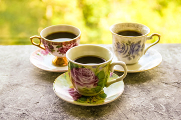 Hot morning coffee in small cups on shabby chic vintage black and white window sill in front of summer window