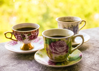 Hot morning coffee in small cups on shabby chic vintage black and white window sill in front of summer window