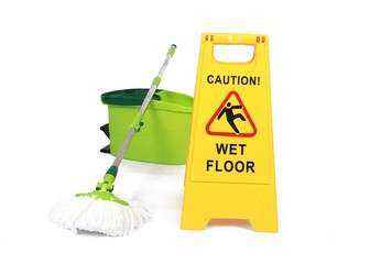 Yellow Caution slippery wet floor sign with mop and bucket in the background - Safety sign cleaning...
