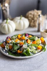 Green salad with baked squash pumpkin, spinach, white cheese and pumpkin seeds on plate